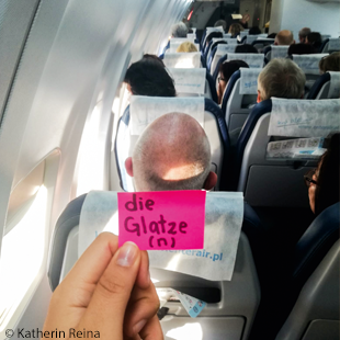 Blick über Flugzeugsitz auf eine Glatze