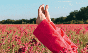 Nackte Frauenfüße vor Blumenfeld