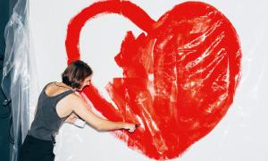Frau malt Herz an Wand