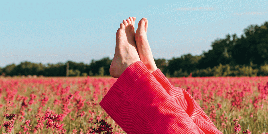 Nackte Frauenfüße vor Blumenfeld