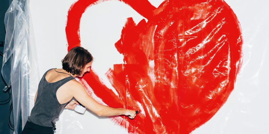 Frau malt Herz an Wand