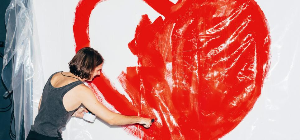 Frau malt Herz an Wand