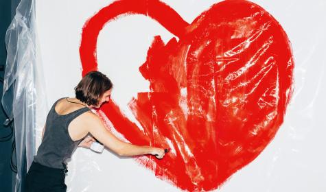 Frau malt Herz an Wand